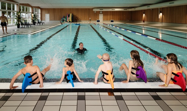 Barn med simdynor på bassängkanten.