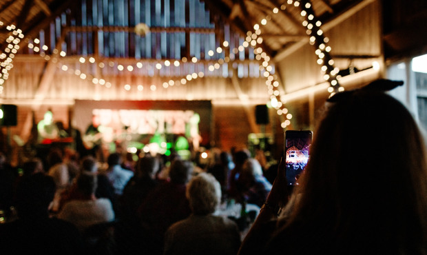 Evenemang i en lada, ljusslingor hänger över publiken.